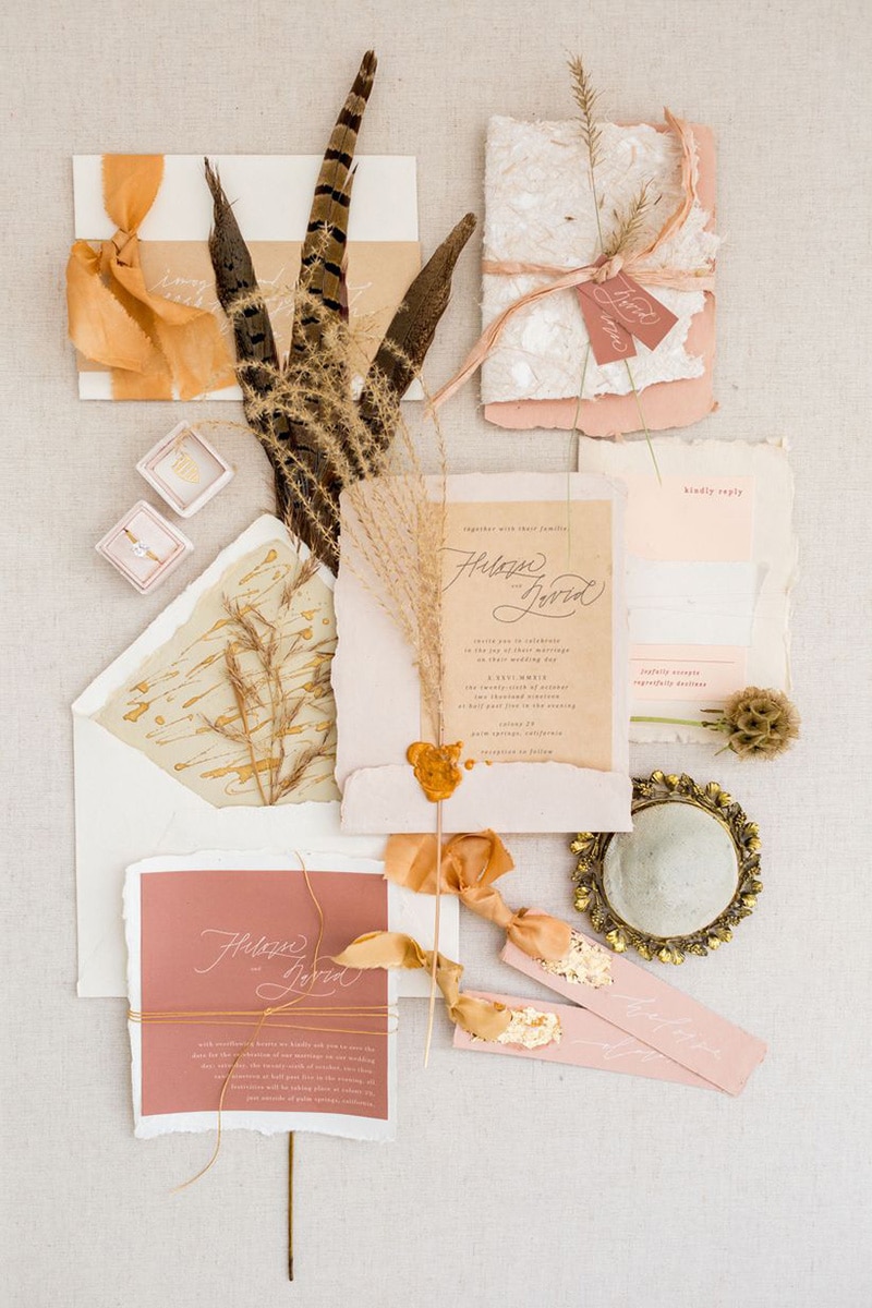Romantic Boho Desert Pastel Wedding Ideas | Eclectic boho wedding stationery suite featuring modern fine line script on deckle edge handmade cotton paper in blush, dusty pink, terracotta and sand tones, finished with ribbon, raffia, gold foil, wax seals and sprigs of dried foliage. | Photography: Kir2Ben via Wedding Wire