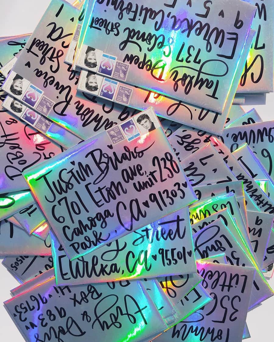 Electric Disco Wedding Ideas |  Holographic wedding invitation envelopes reflecting rainbow colours with bold cursive lettering written in thick black marker | Photography: Christina Winkelmann