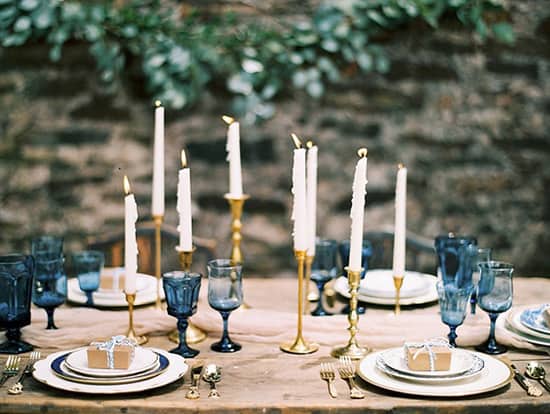 Wedding reception centrepiece with gold candlesticks and blue glassware | Anna K. Photography via Southern Weddings