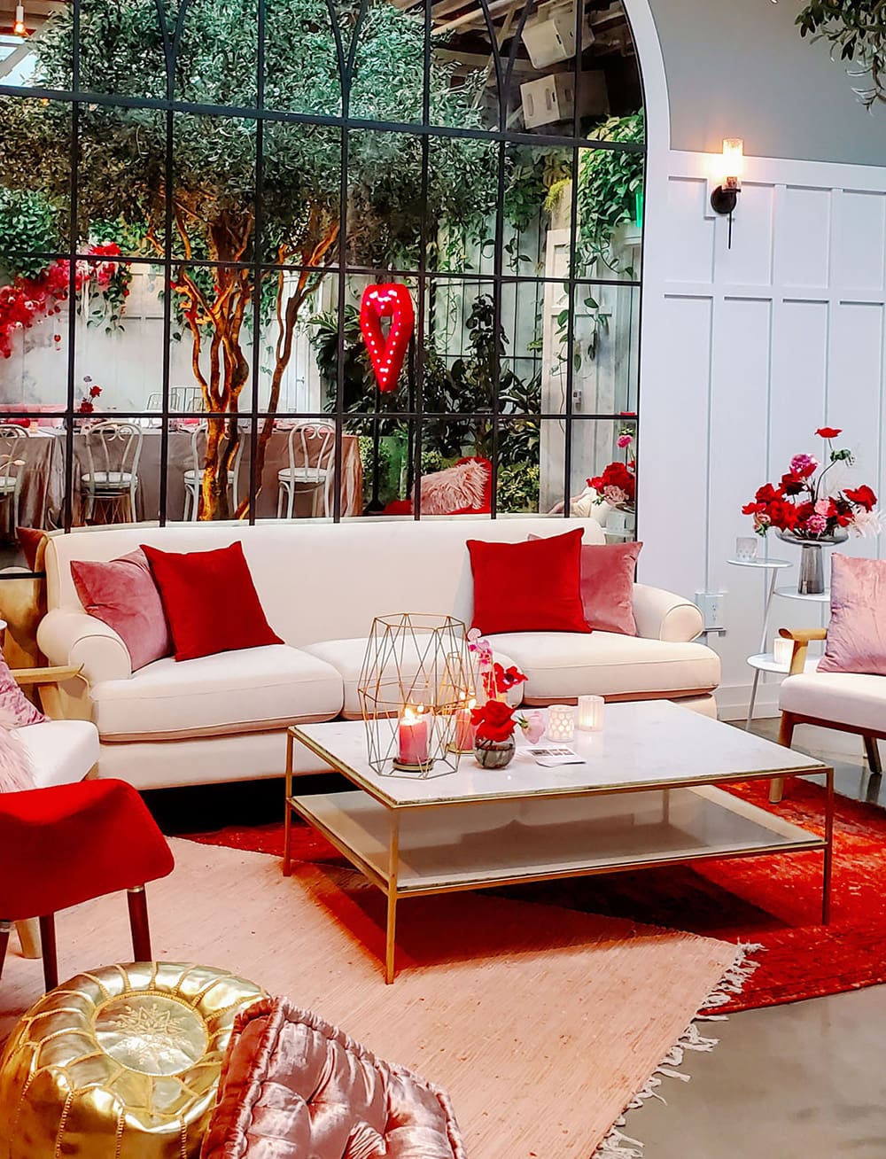 Modern Red & Pink Wedding Ideas | A modern wedding reception lounge setting featuring a white lounge decorated with red and pink pillows, a white coffee table with gold edges topped with candles and layered pink and red rugs. | Photography: Madeline Kate Photography via Together Journal