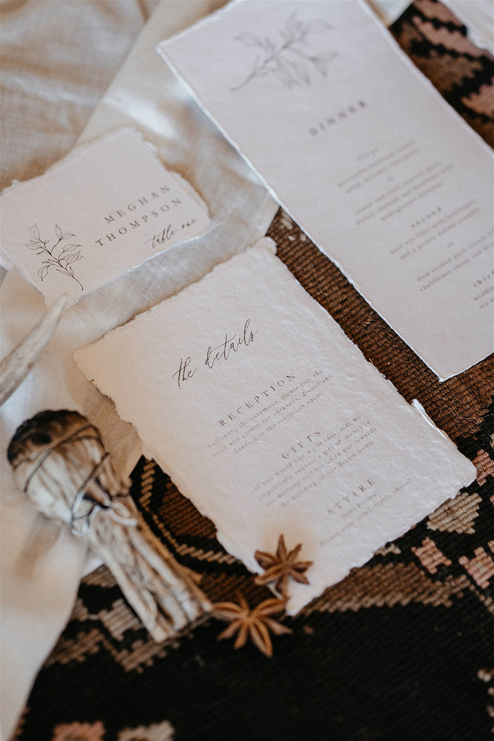 Outdoor Festival Bohemian Wedding Inspiration | A boho wedding stationery suite on white deckle edge cotton paper features a fine line foliage motif and modern vintage serif font paired with flowing script. The suite consists of a wedding invitation, a card providing "The Details" on the reception, gifts and attire, a "Kindly Respond By" RSVP card, an escort card with the guest name and table number, and a dinner menu. | Photography: Shae Estella Photo
