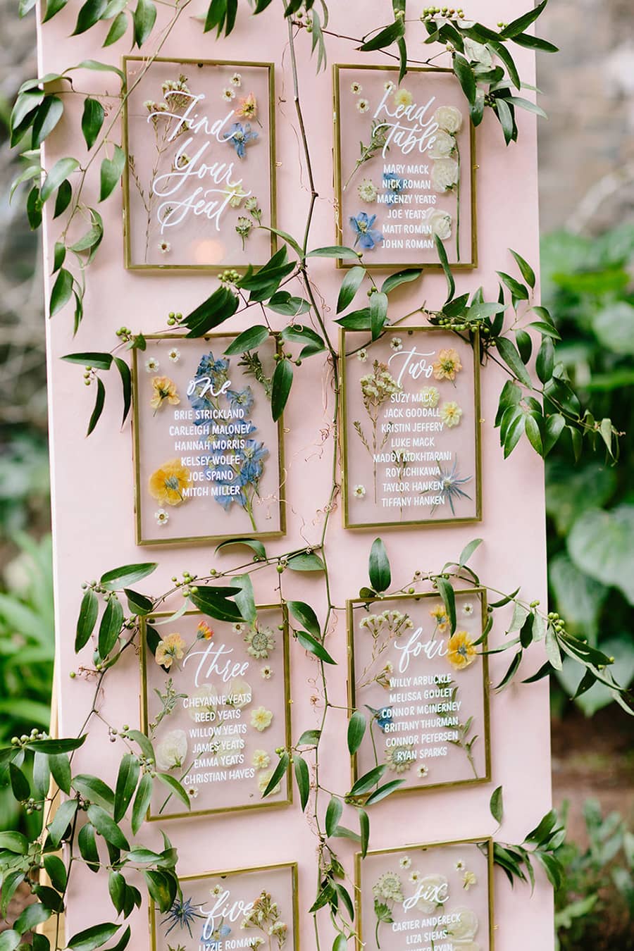 Spring Pastel Wedding Ideas | Romantic wedding reception seating chart featuring a blush pink backdrop, gold frames, pressed flowers and trailing greenery. | Photography: Melia Lucida via 100 Layer Cake