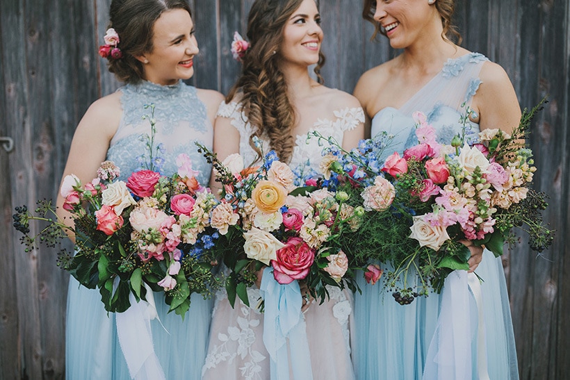 Bridesmaids wearing romantic ice blue lace dresses and carrying bright multicolour bouquets for whimsical garden wedding | Lover of Mine