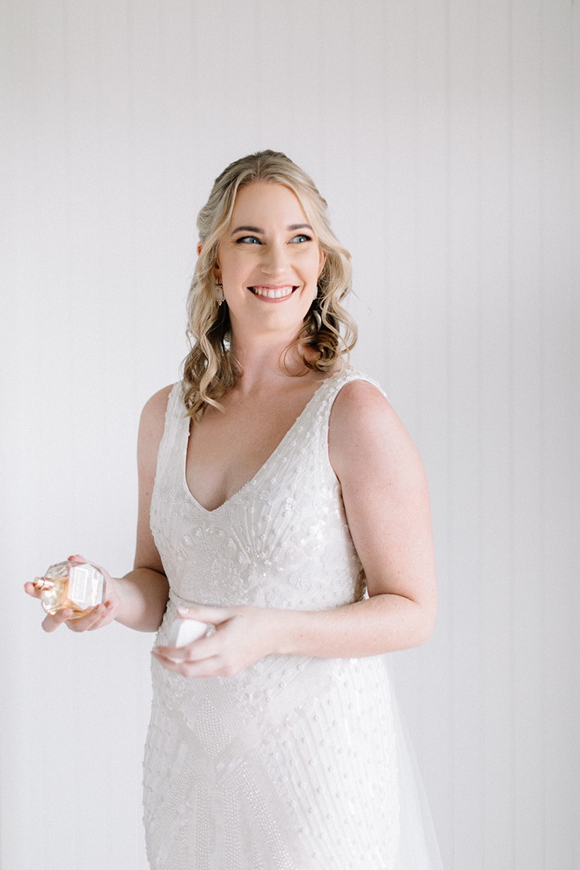 Bride in beaded ivory wedding dress spraying signature perfume | Nattnee Photography